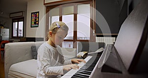 Little girl playing piano at home. Kid play piano in living room. Child learning piano at home. Music lesson, medium