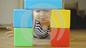 Little girl playing plastic toy cubes in a children`s room