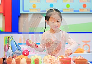 Little girl playing pretend as a sale in ice-cream shop