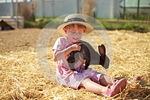 Little girl playing with rabbits on a sunny summer or spring day at sunset.