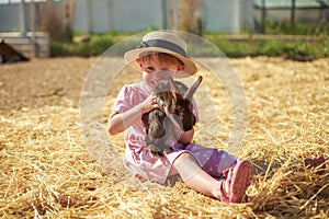 Little girl playing with rabbits on a sunny summer or spring day at sunset.