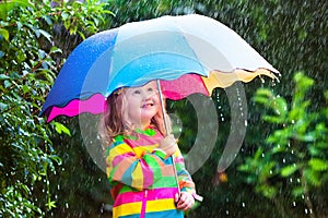 Little girl playing in the rain under umbrella