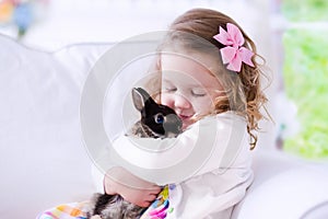 Little girl playing with a real pet rabbit