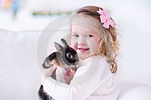 Little girl playing with a real pet rabbit