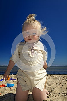 Little girl playing in the sand on the beach by the sea