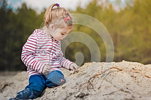 Little girl playing with sand in the forest