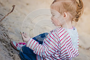 Little girl playing with sand in the forest