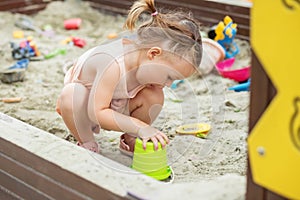 Little girl playing in sandbox at playground outdoors. Toddler playing with sand molds