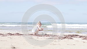 Little girl playing on a sandy beach by the sea