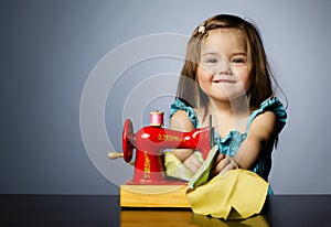 Little girl is playing with sewing machine