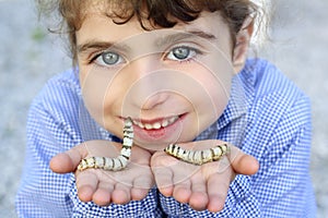 Little girl playing with silkworm in hands