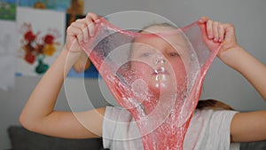 Little girl playing with slime, make bubble, pulls on face, have fun close up
