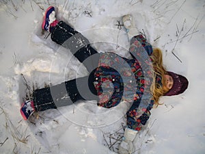 Little girl playing snow angel