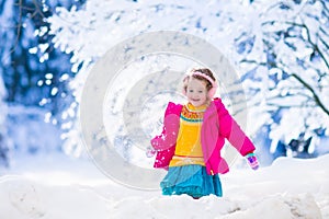 Little girl playing snow ball fight in winter park