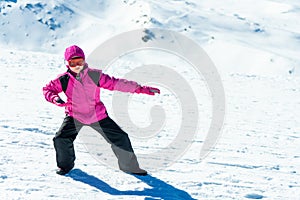 Little girl playing snowboard trainer on snow