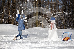 Little girl playing with a snowman