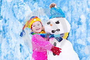 Little girl playing with a snowman