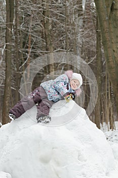 Little girl playing on snowy hill in beautiful