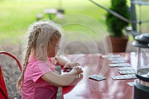 Little girl playing solitaire at an outdoor table