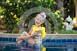 Little girl playing and spraying water in swimming pool outdoors at summer. Summer vacation concept