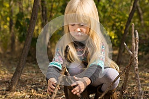 Little girl playing with sticks in woodland