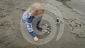 Little girl is playing with stones on a bank of river