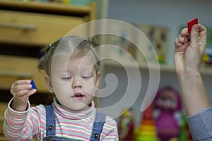 Little girl playing and studying on lessons in kindergarden