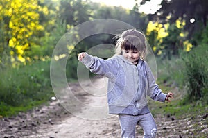 Little girl playing in sunny blooming forest. Toddler child picking flowers. Summer fun for family with children.