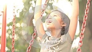 Little girl playing on swing in summer day