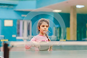 Little girl playing table tennis in the tennis hall,