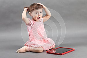 Little girl playing with tablet computer on the floor