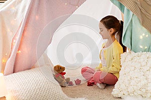 Little girl playing tea party in kids tent at home