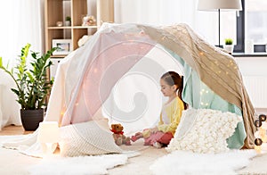 Little girl playing tea party in kids tent at home