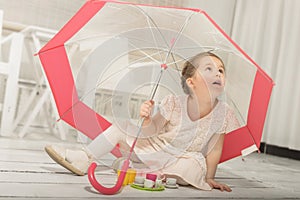Little girl playing tea party sitting under an umbrella