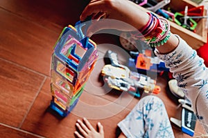 Little girl playing to build a tower with magnetic pieces of plastic colors