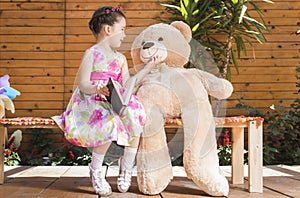Little girl playing with toy bear outside