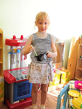 Little girl playing with toy kitchen