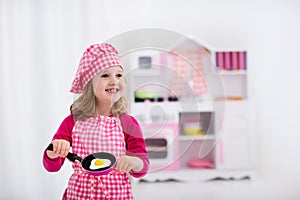 Little girl playing with toy kitchen