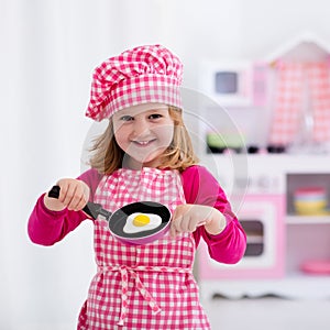 Little girl playing with toy kitchen