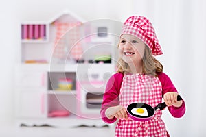 Little girl playing with toy kitchen