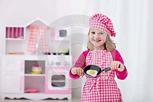 Little girl playing with toy kitchen