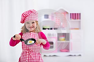 Little girl playing with toy kitchen