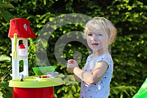 Little girl playing with toy kitchen outdoors