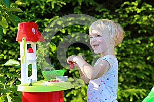 Little girl playing with toy kitchen outdoors