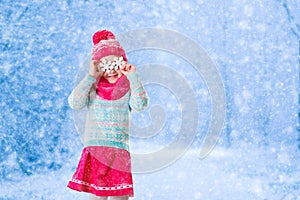 Little girl playing with toy snow flakes in winter park