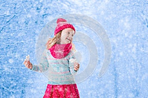 Little girl playing with toy snow flakes in winter park