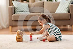 Little girl playing with toy tea set at home