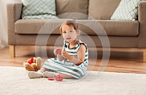 Little girl playing with toy tea set at home