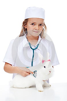 Little girl playing veterinary with her rabbit