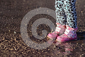 Little girl is playing in water, dirty shoes, the flight of water droplets, unforgettable moments, children`s entertainments, con